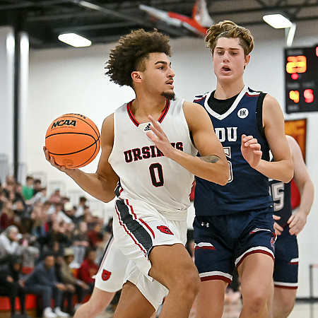 Ursinus College Basketball player dribbling the ball during a game with defender.