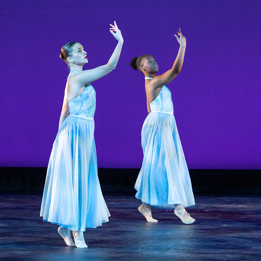 Two girls performing a synchronized dance routine on stage.