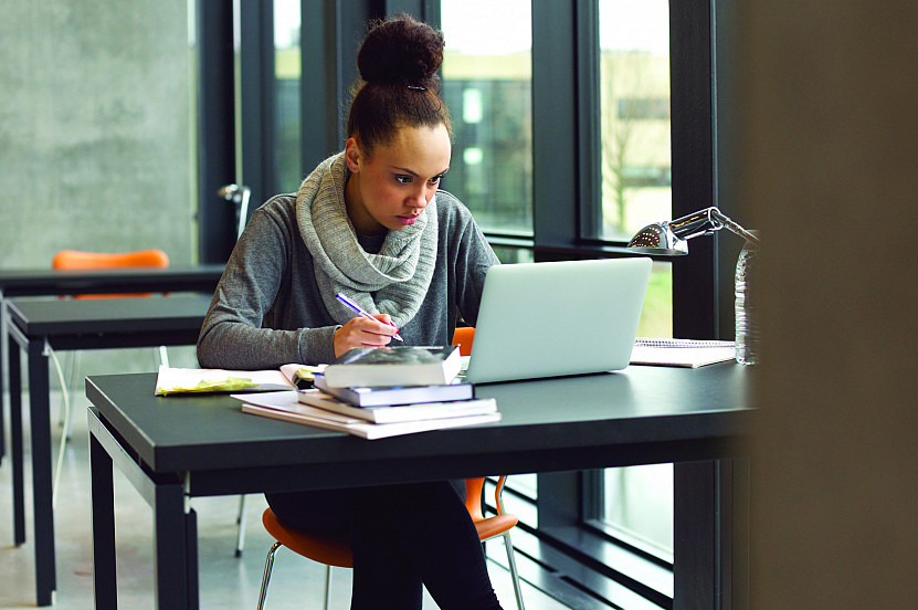 Female student taking notes on laptop