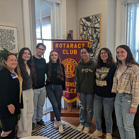 Photo of seven people in front of a banner reading Rotaract Club Ursinus College the students are Rotaract Club Officers 2024-25