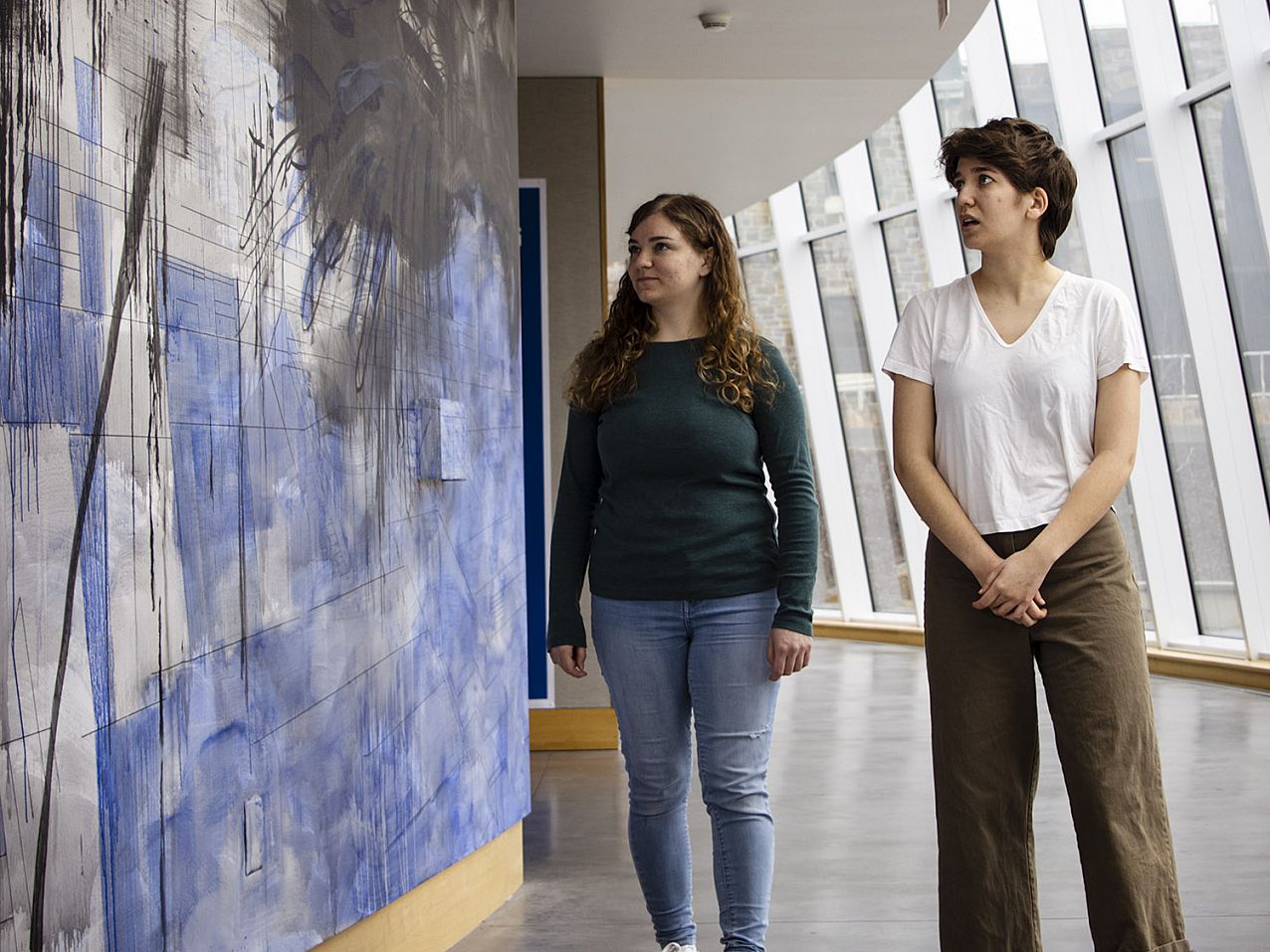 Students walking around an the art gallery examining work on the wall.