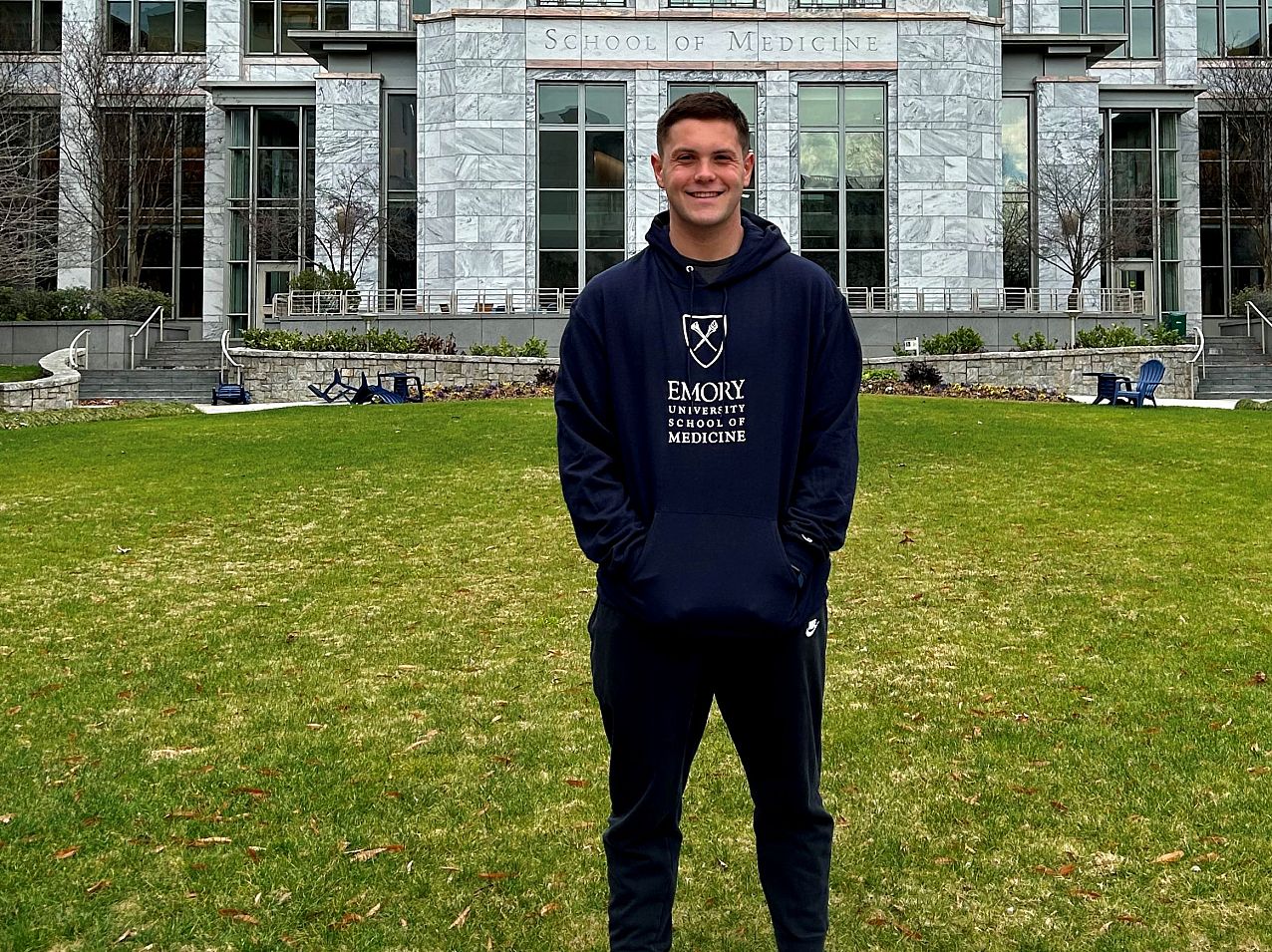 Student standing in front of the School of Medicine on campus.