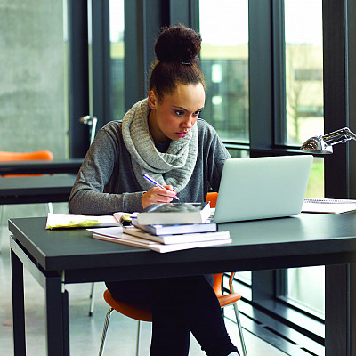 Female student taking notes on laptop