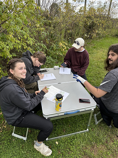 Students in the 2023 capstone class work on their signage plans in a welcoming and now well-vegetated Phase I site.