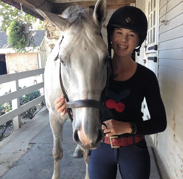 Neva stands next to her horse with a big smile.