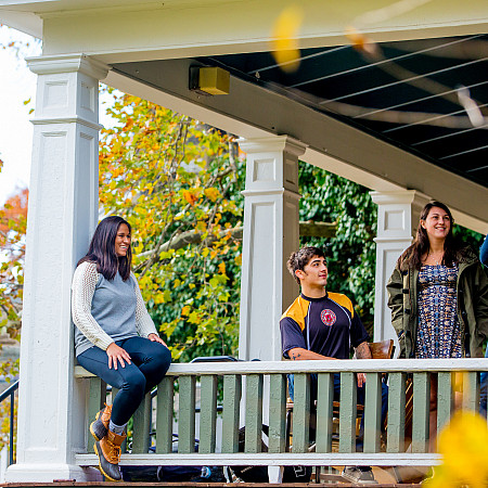 Students talking on the porch of a Main Street house.